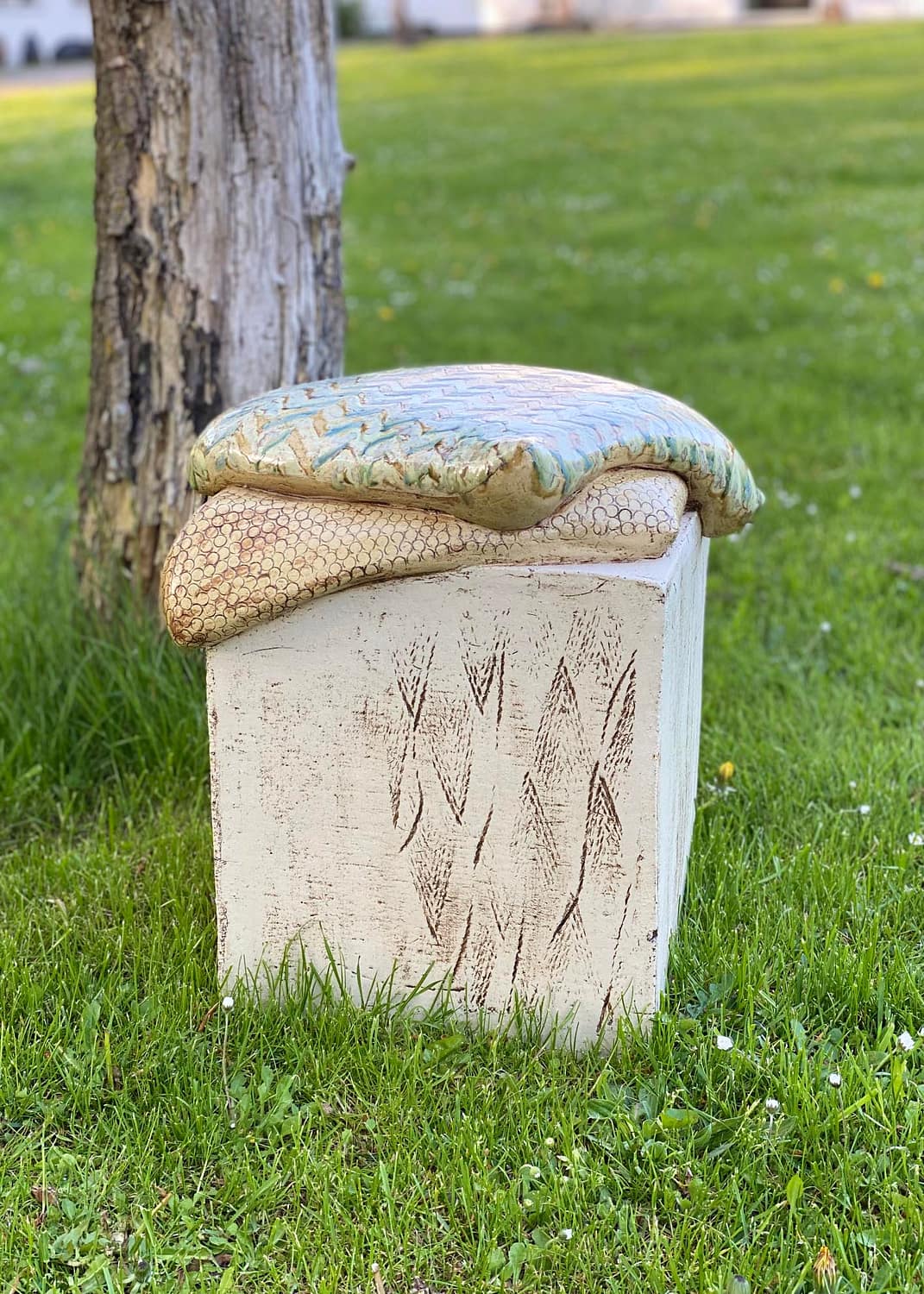 Keramisk skulptur med 2 puder på en græsplæne