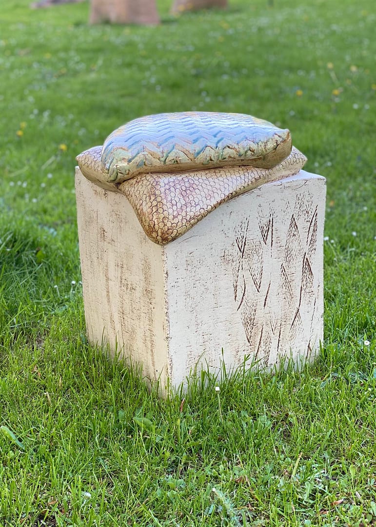 Keramisk skulptur med 2 puder på en græsplæne